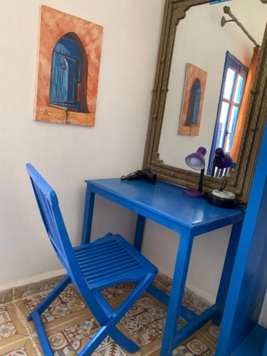 a blue desk with a chair and a mirror at Chez Youssef in Merzouga
