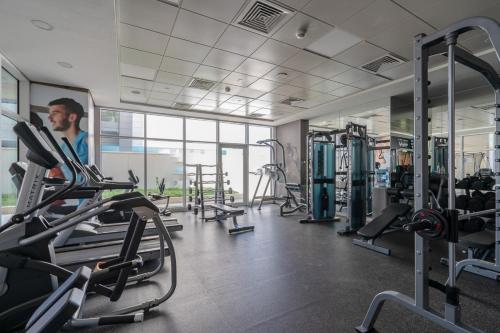 a gym with tread machines and a man in the background at Cozy 1br in Parkside A in Abu Dhabi