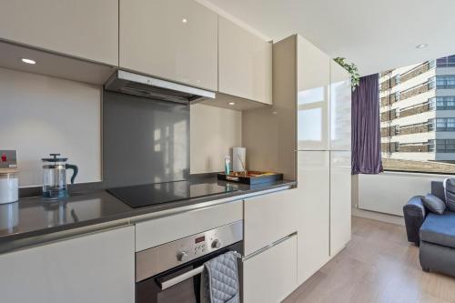 a kitchen with white cabinets and a stove top oven at Family Apart for 6 Easy Booking in Sunbury Common