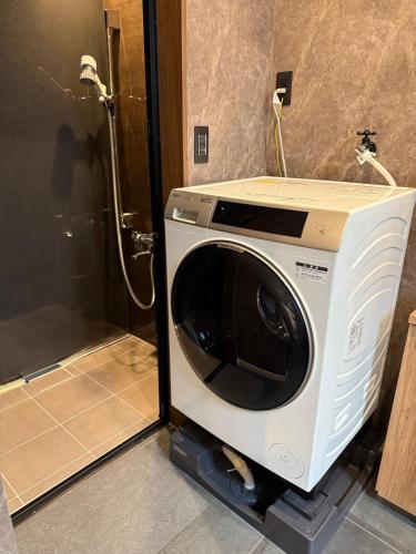 a washing machine sitting in the corner of a bathroom at EKVOLI ROPPONGI TOKYO, Private Hotel in Tokyo