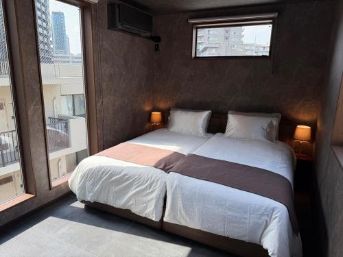 a bedroom with a large bed with two windows at EKVOLI ROPPONGI TOKYO, Private Hotel in Tokyo