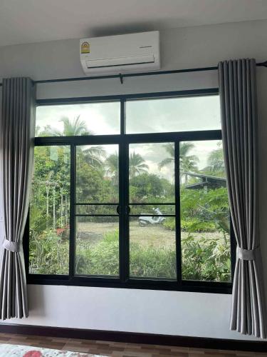 a window with a view of a palm tree at โอบวิว โฮม Oabview Home in Ban Choko