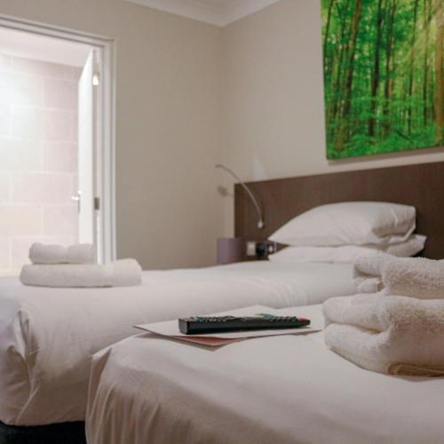 two white beds with a remote control on top of them at The Dormy House Hotel in Cromer