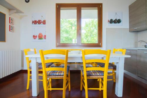 a kitchen with a white table and yellow chairs at swimming pool and private garden, Casa in collina in Barcuzzi