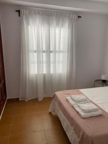 a bedroom with a bed and a window with white curtains at BRISA del MAR in Isla Cristina