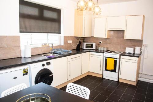 a kitchen with white cabinets and a washer and dryer at Comfortable 3 bed house in Manchester