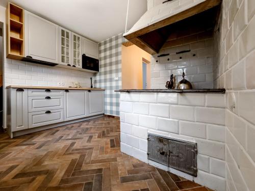 una cucina con mobili bianchi e pavimento in legno di Niezapominajka Zabłocie 145 