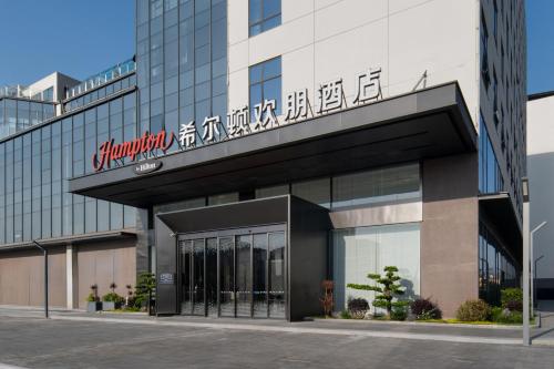 a building with a sign on the front of it at Hampton by Hilton Guangzhou Baiyun Airport Cultural Tourism City in Guangzhou