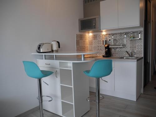 - une cuisine avec 2 chaises bleues et un comptoir dans l'établissement La Grande Motte by la Paillère, à La Grande Motte