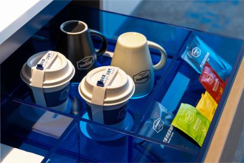 three coffee cups sitting on a glass shelf at Hampton by Hilton Guangzhou Baiyun Airport Cultural Tourism City in Guangzhou