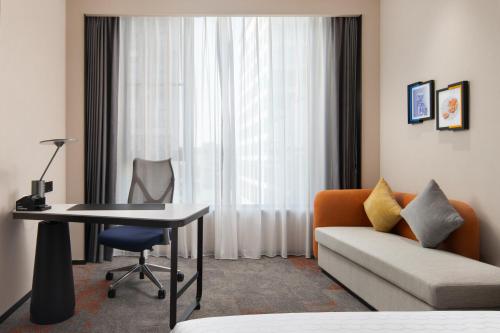 a living room with a couch and a table and a chair at Hampton by Hilton Guangzhou Baiyun Airport Cultural Tourism City in Guangzhou