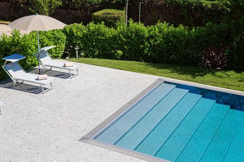a swimming pool with two chairs and an umbrella at Hotel Mealba in Saronno