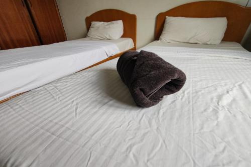 two beds with a towel sitting on top of them at Hotel Check Inn 2 Cameron Highlands in Brinchang