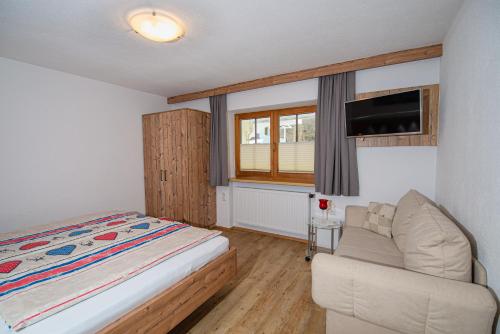 a bedroom with a bed and a couch and a tv at Landhaus Exenberger / Ferienwohnung Smaragd in Bramberg am Wildkogel