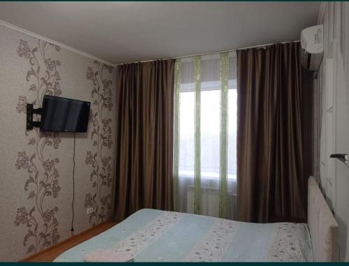 a bedroom with a bed and a window at Квартира in Aktobe