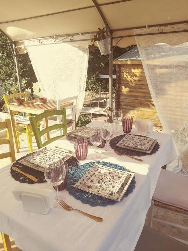 a white table with plates and wine glasses on it at B&B Luxury Villa Olimpia Home Restaurant in Selva di Fasano
