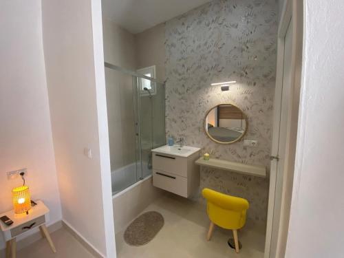 Un baño con un lavabo, un espejo y una silla amarilla. en Sol Sherry, en Jerez de la Frontera