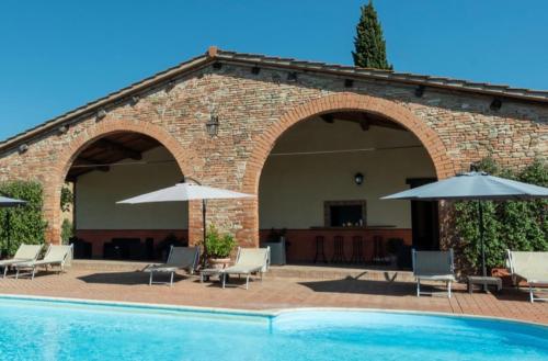 a pool with chairs and umbrellas next to a brick building at Country House Le Case Coloniche in Deruta