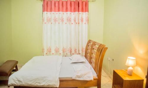 a bedroom with a bed with a curtain and a table at Amani home in Nkunjila