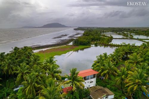 an aerial view of a beach with palm trees and a building at EKOSTAY Luxe - Oceanic Villa in Alibaug