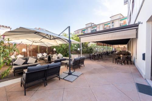 a patio with tables and chairs and umbrellas at Hotel Palace Verona in Verona