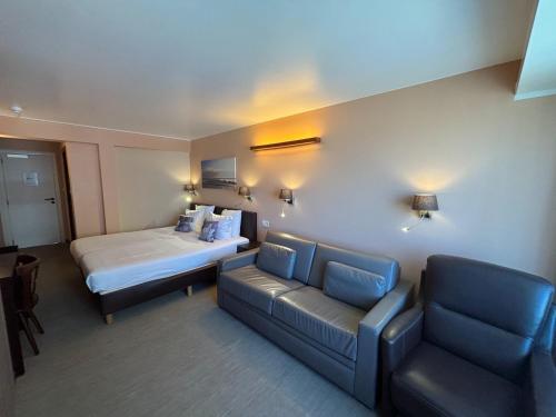 a hotel room with a bed and a couch at Hotel Uilenspiegel in Nieuwpoort
