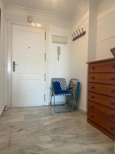 a room with a door and a chair and a dresser at Benalmadena Suite Vistas panorámicas, 2 piscinas, Area infantil, Bar, Jardines y Tenis in Benalmádena
