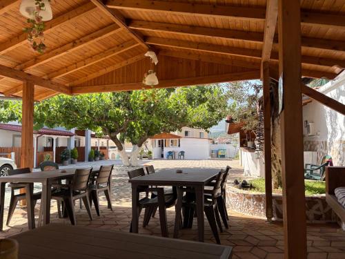 a patio with tables and chairs under a wooden pergola at Yard Paradise in Dhërmi