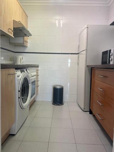 a kitchen with a washing machine and a refrigerator at Benalmadena Suite Vistas panorámicas, 2 piscinas, Area infantil, Bar, Jardines y Tenis in Benalmádena