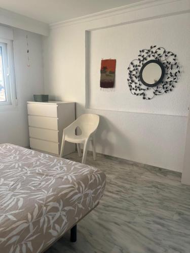 a bedroom with a bed and a chair and a mirror at Benalmadena Suite Vistas panorámicas, 2 piscinas, Area infantil, Bar, Jardines y Tenis in Benalmádena