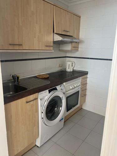 a kitchen with a washing machine and a sink at Benalmadena Suite Vistas panorámicas, 2 piscinas, Area infantil, Bar, Jardines y Tenis in Benalmádena