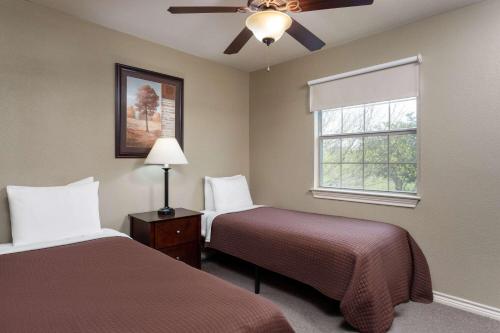 a bedroom with two beds and a ceiling fan at Eagle's Den Three Rivers Texas a Travelodge by Wyndham in Three Rivers