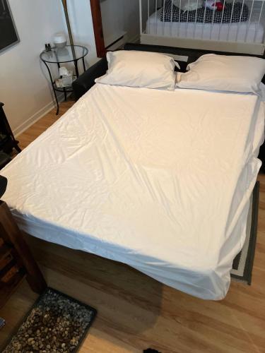 a large bed with white sheets and pillows at Traversier Gratuit- Aux Trois Filles in Lévis