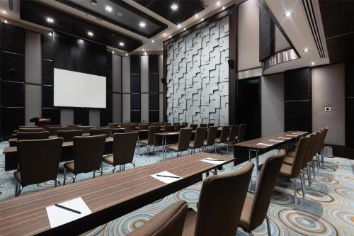 a conference room with tables and chairs and a projection screen at Radisson Blu Hotel, Dubai Media City in Dubai
