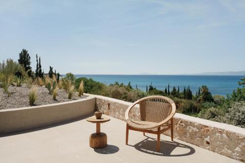 a rattan chair sitting on a patio overlooking the ocean at Sundara Estate, Exclusive Seaview Villa with Grand Pool & Direct Beach Access in Ratzaklíon