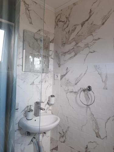 a white bathroom with a sink and a mirror at Cozzy apartment near the Aiport Podgorica in Mitrovići