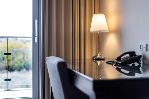 a desk with a lamp and a chair next to a window at Scandic Opus Horsens in Horsens