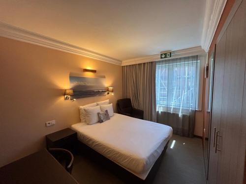 a hotel room with a bed and a window at Hotel Uilenspiegel in Nieuwpoort