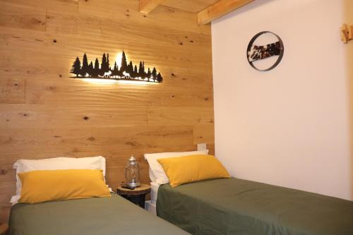 two beds in a room with wooden walls at Miki's Home - 2 bagni e giardino privato in Ponte di Legno