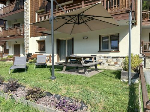 a picnic table and chairs under an umbrella in a yard at Miki's Home - 2 bagni e giardino privato in Ponte di Legno