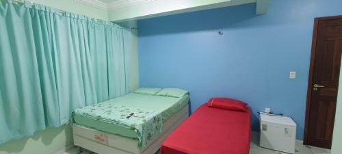a small bedroom with a bed and a red bench at Hotel Marajoara Breves in Breves