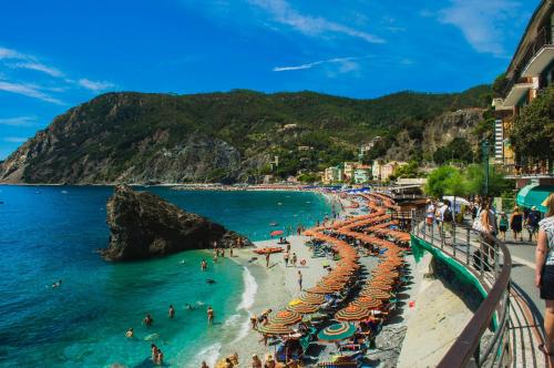 a beach with umbrellas and people in the water at Onde & Orizzonti Vista Torre in Vernazza