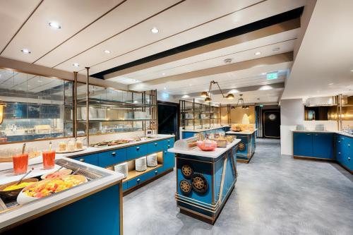 a large kitchen with blue cabinets and food at Radisson Blu Senator Hotel, Lübeck in Lübeck