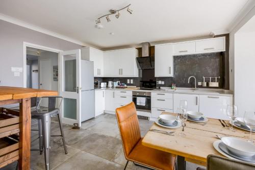 a kitchen with white cabinets and a wooden table at Candle Island View - Superb Harbour Views from Three Floors in Poole