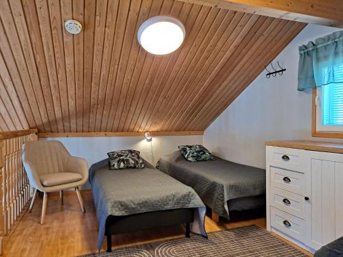 a small room with two beds and a chair at Metsätuuli 4 in Kalajoki