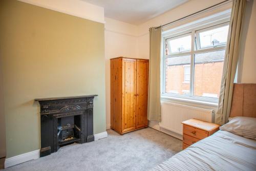 a bedroom with a fireplace and a bed and a window at Lovely Lindisfarne in Carlisle