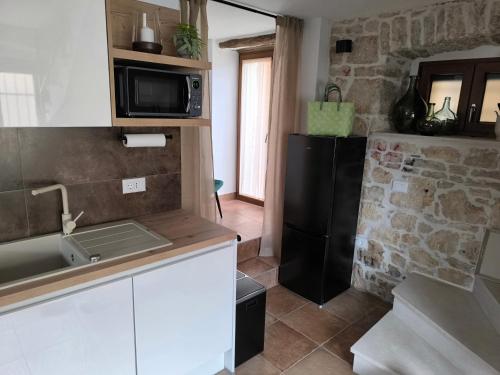 La cuisine est équipée d'un évier et d'un réfrigérateur noir. dans l'établissement Steinhaus Casa Lapidaria, à Višnjan