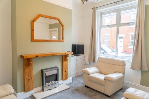 a living room with a fireplace and a chair and a mirror at Lovely Lindisfarne in Carlisle
