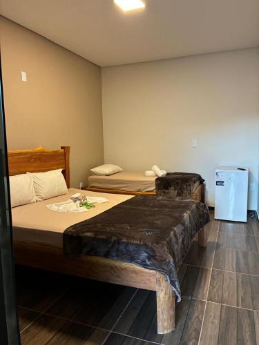 a bedroom with two beds and a small refrigerator at Pousada Lapa Rupestre in Santana do Riacho