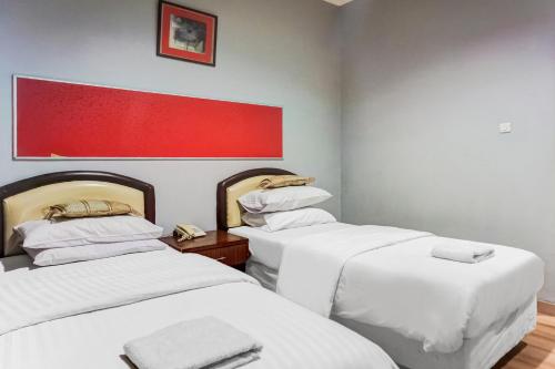 a room with two beds and a red painting on the wall at Townhouse Oak Syariah Hotel Binjai in Medan